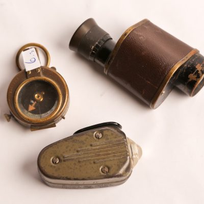 6   Military items.  Hand      generated light (Phillips  Co.); single lens binocular;  brass compass (marked E.Hoehn  - 1917). Three pieces.   